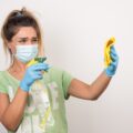 mujer-joven-mascarilla-rociando-sobre-tela-pared-blanca-1